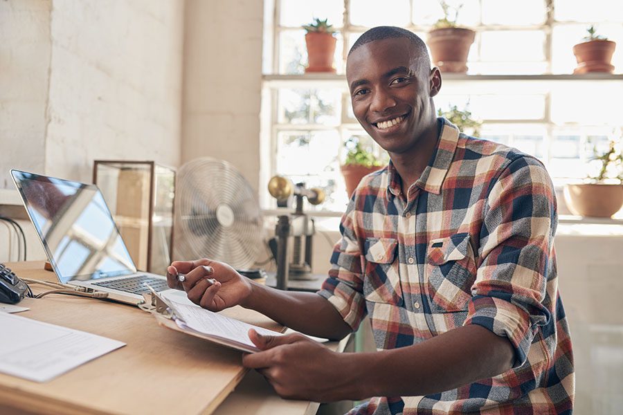 Business Insurance - Portrait Of Young Small Business Owner Sitting In His Office